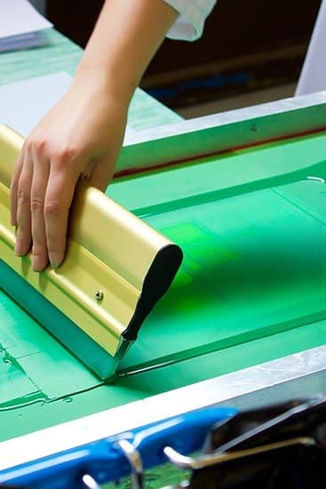 Dye being pulled across a mesh screen by hand, printing a length of cotton